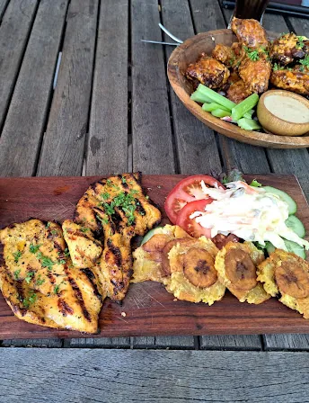 Pechuga a la plancha geserveerd op een houten plank met friet, bakbanaan en groenten